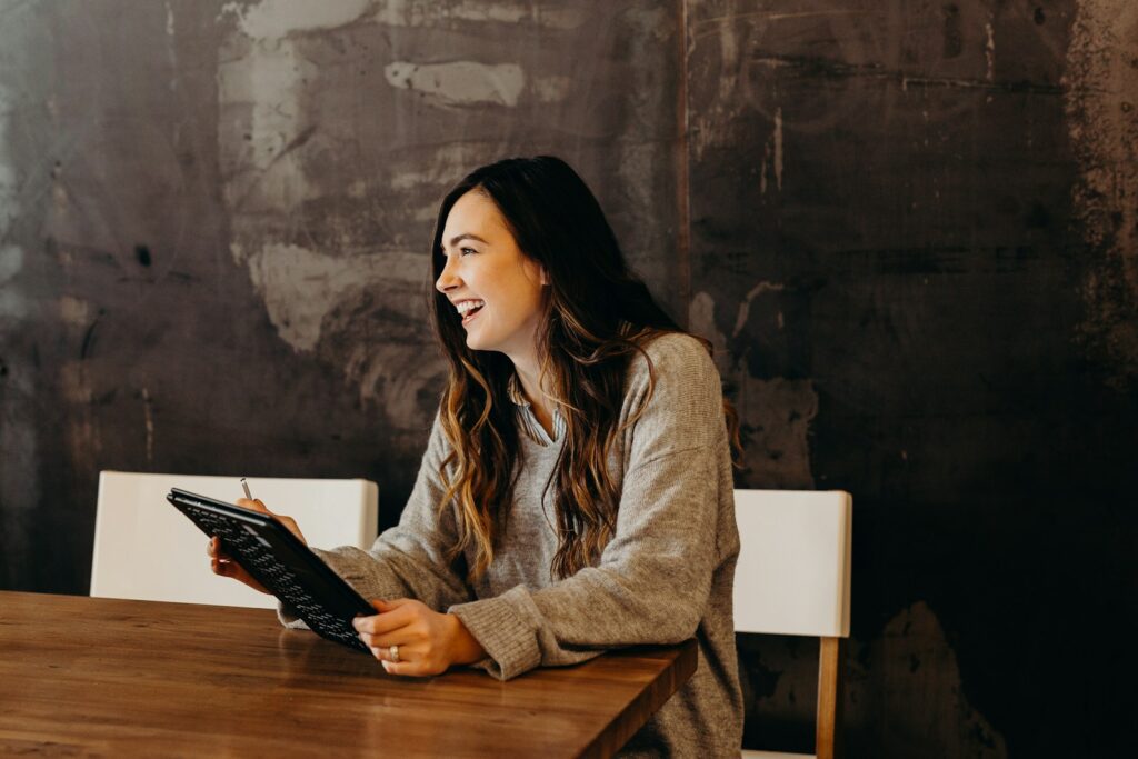 woman sitting around table holding tablet, cómo atraer clientes sin pagar publicidad